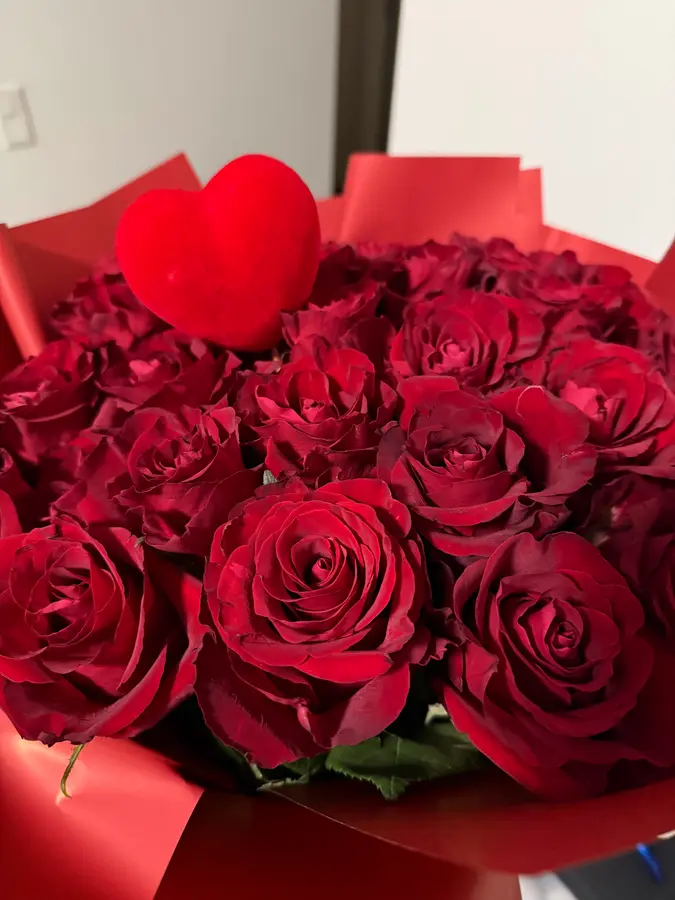 Rote Rosen in rotem Papier mit einem Herz