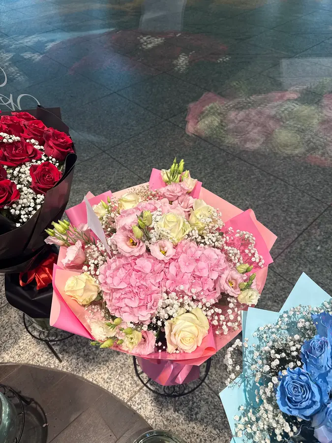 Rosa Hortensien und Rosen in pinkem Papier im Bahnhof
